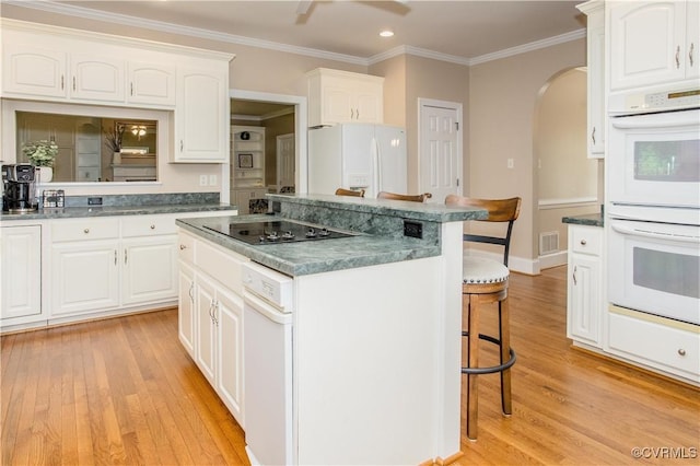 kitchen featuring white appliances, visible vents, arched walkways, a kitchen island, and a kitchen breakfast bar