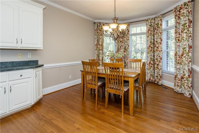 dining room with light wood finished floors, visible vents, baseboards, crown molding, and a chandelier