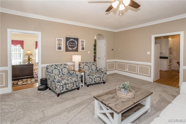 living area with arched walkways, crown molding, and wainscoting