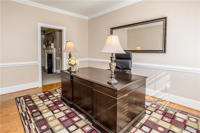 home office featuring baseboards, a fireplace, crown molding, and light wood finished floors