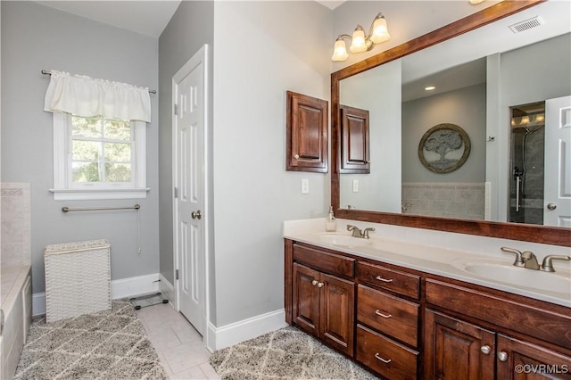 bathroom with double vanity, a washtub, visible vents, and a sink