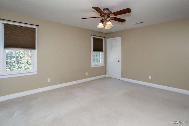 unfurnished room featuring light carpet, visible vents, a ceiling fan, and baseboards