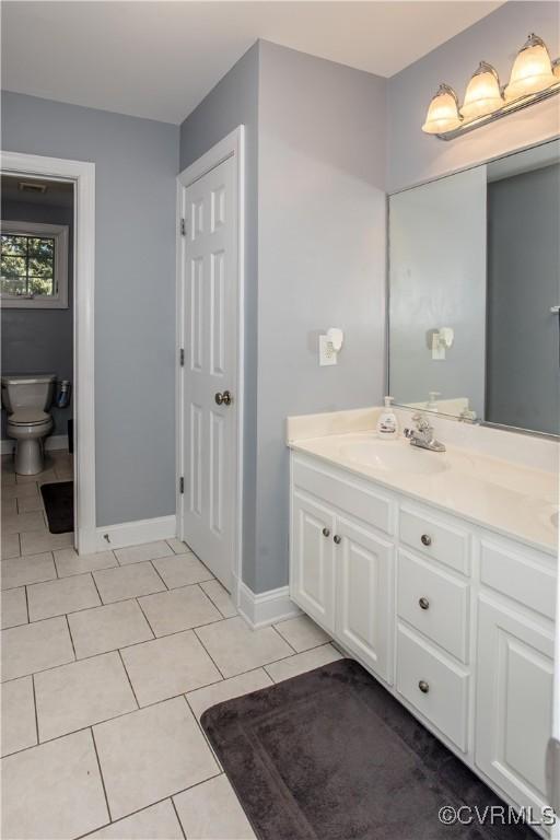 bathroom with baseboards, vanity, toilet, and tile patterned floors