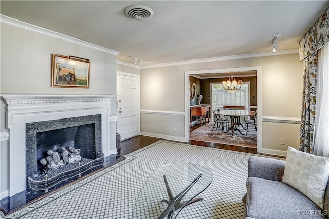 living room featuring dark wood-type flooring, ornamental molding, an inviting chandelier, and a fireplace