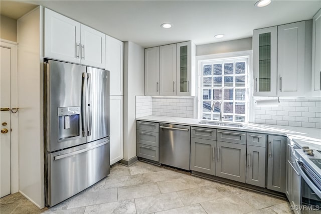 kitchen with appliances with stainless steel finishes, tasteful backsplash, sink, and gray cabinetry