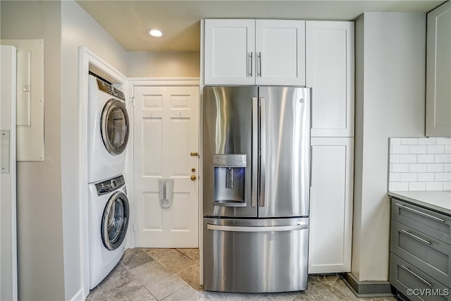 kitchen featuring white cabinetry, stainless steel refrigerator with ice dispenser, and stacked washing maching and dryer