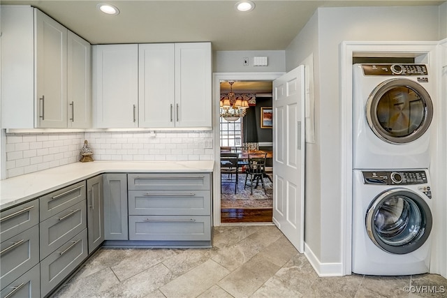 laundry room with stacked washer / dryer and a chandelier