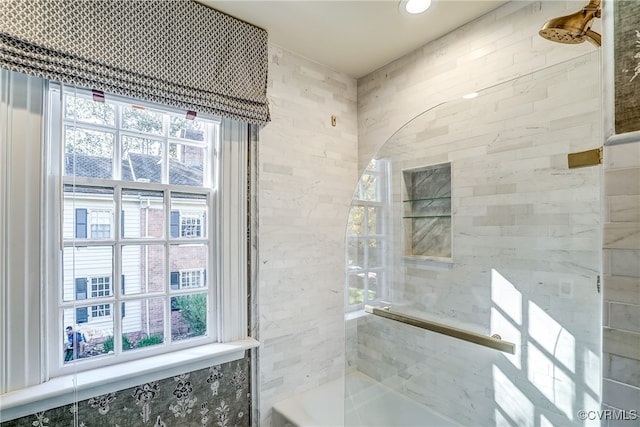 bathroom with a wealth of natural light, tile walls, and tiled shower