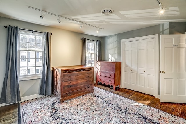 bedroom with a closet, multiple windows, wood-type flooring, and rail lighting