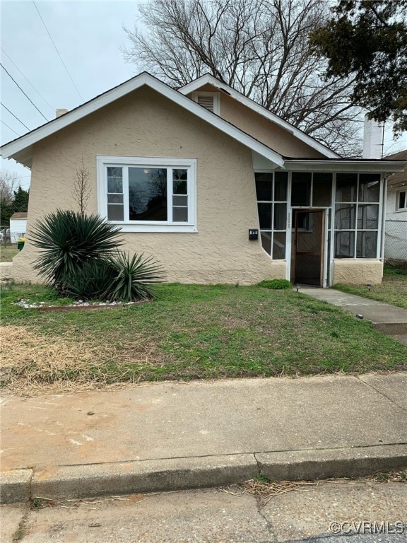 view of front of house with a front yard and a sunroom