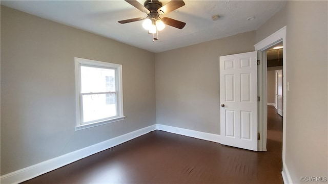 empty room with ceiling fan and dark hardwood / wood-style floors