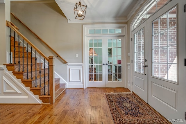 doorway to outside featuring ornamental molding, a chandelier, french doors, and light hardwood / wood-style floors