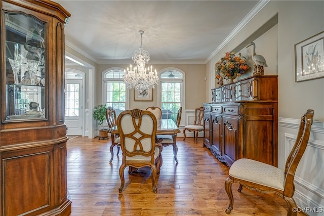 dining area with an inviting chandelier, light wood-type flooring, and crown molding