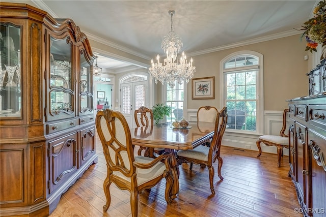 dining room featuring light wood-type flooring, crown molding, and an inviting chandelier