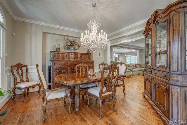 dining space featuring light wood-type flooring, crown molding, and an inviting chandelier