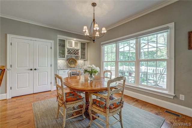 dining room featuring an inviting chandelier, light wood-type flooring, and crown molding