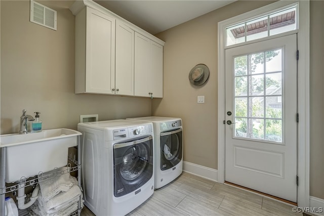 laundry room with washing machine and clothes dryer and cabinets