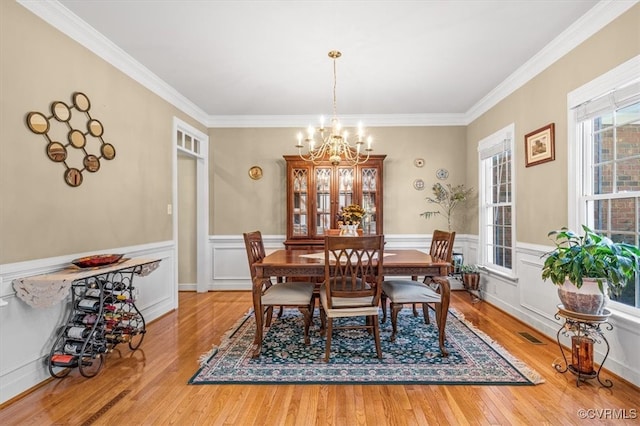 dining area featuring crown molding, light hardwood / wood-style floors, and a notable chandelier