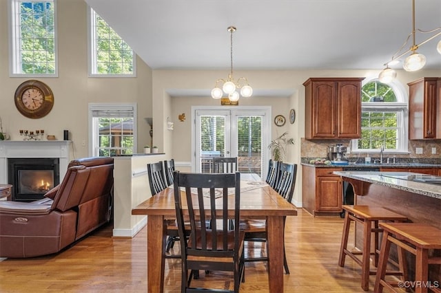 dining room with a wealth of natural light, a notable chandelier, and light wood-type flooring