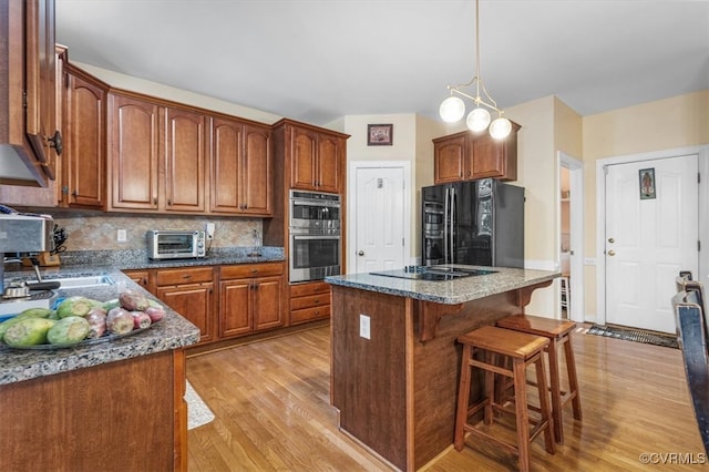 kitchen featuring dark stone counters, a center island, black appliances, and light hardwood / wood-style floors