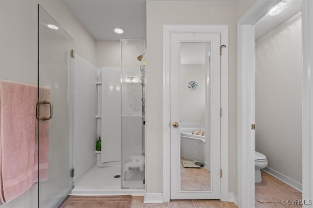 bathroom featuring toilet, a shower with door, and tile patterned flooring