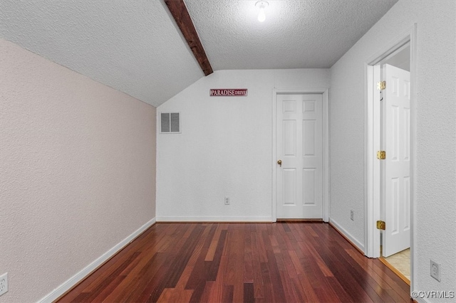 additional living space with lofted ceiling with beams, dark wood-type flooring, and a textured ceiling