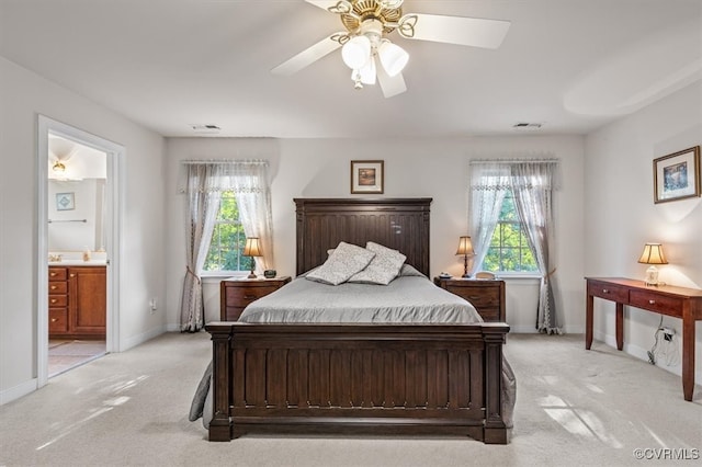 bedroom with ensuite bathroom, ceiling fan, light colored carpet, and multiple windows