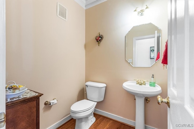 bathroom featuring hardwood / wood-style flooring, toilet, and crown molding