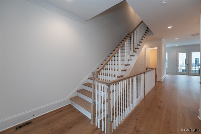 stairway featuring crown molding, french doors, and wood-type flooring