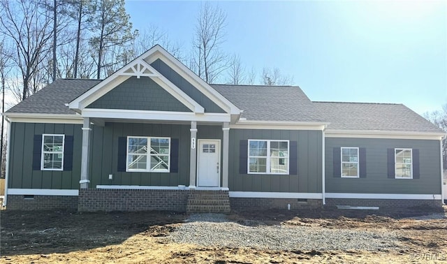 view of front facade featuring a shingled roof, crawl space, a porch, and board and batten siding