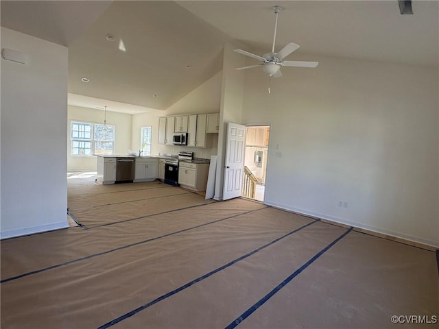 kitchen featuring light countertops, appliances with stainless steel finishes, open floor plan, white cabinetry, and high vaulted ceiling