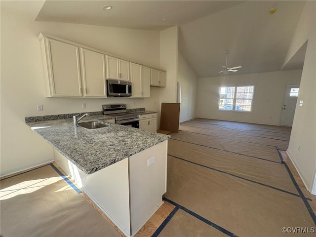 kitchen featuring stainless steel appliances, white cabinets, a sink, light stone countertops, and a peninsula