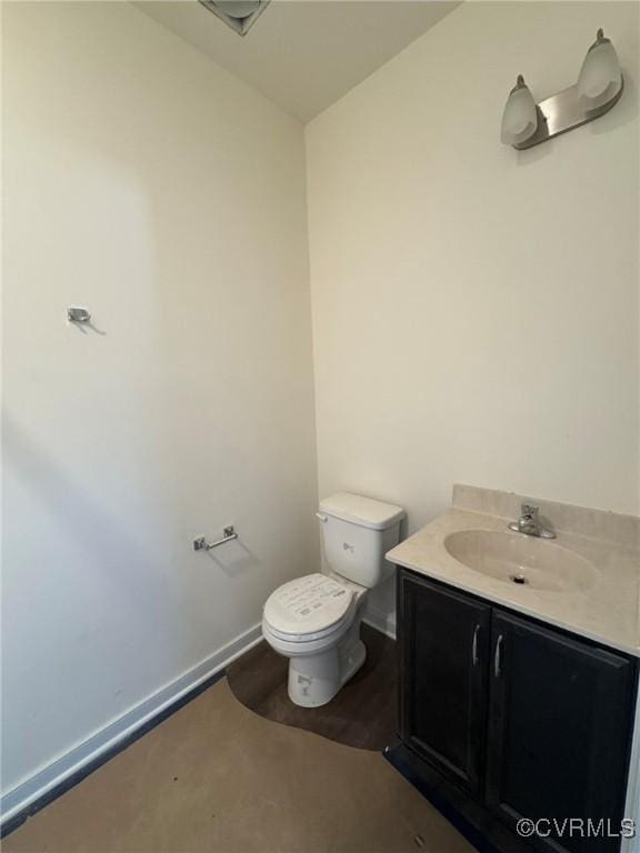 half bathroom featuring toilet, baseboards, and vanity