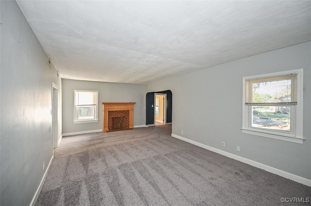 unfurnished living room with a fireplace, carpet flooring, and a textured ceiling