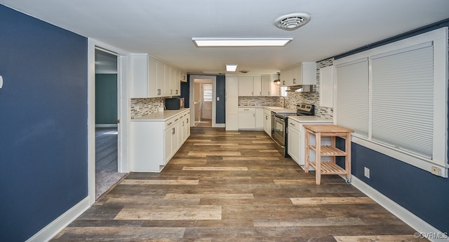 kitchen featuring dark wood-type flooring, white cabinetry, backsplash, and stainless steel electric range