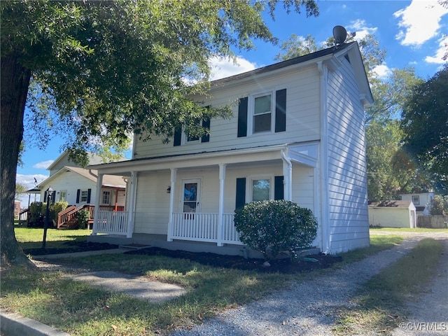 view of front of property featuring a storage shed, a porch, and a front yard