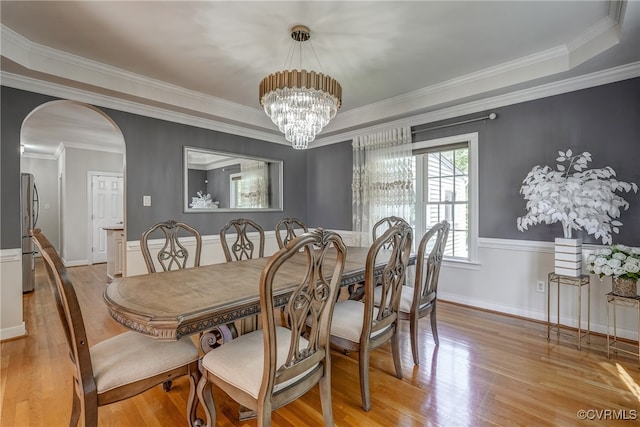 dining space with light hardwood / wood-style floors, ornamental molding, and an inviting chandelier