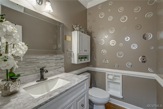 bathroom featuring tasteful backsplash, ornamental molding, vanity, hardwood / wood-style flooring, and toilet