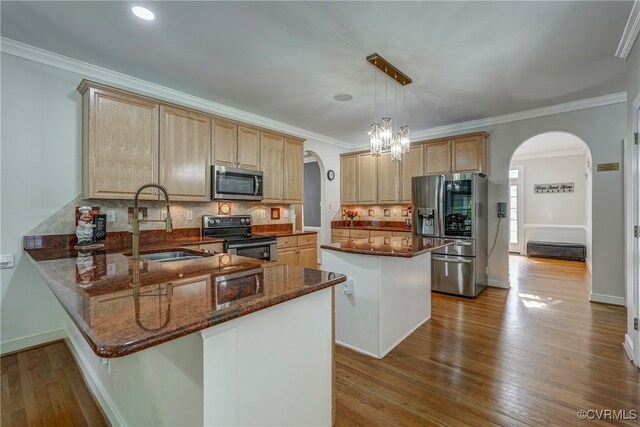 kitchen with sink, a kitchen island, light wood-type flooring, and appliances with stainless steel finishes