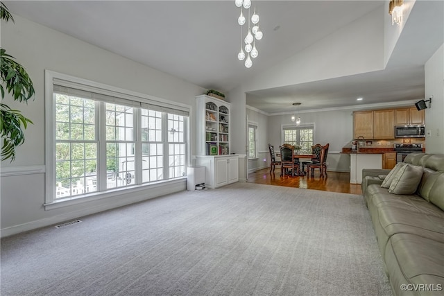 living room with ornamental molding, lofted ceiling, light hardwood / wood-style floors, and a healthy amount of sunlight