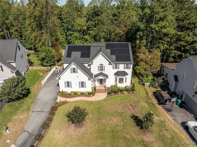 view of front of property featuring solar panels and a front lawn