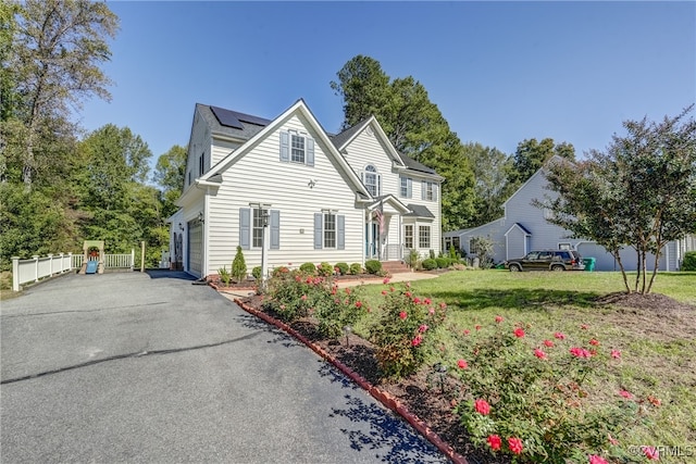 view of front of house with solar panels, a garage, and a front lawn