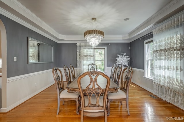 dining space featuring hardwood / wood-style flooring, ornamental molding, and an inviting chandelier