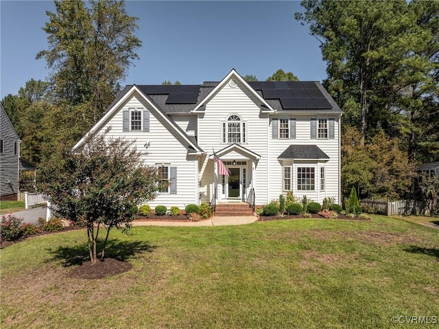 view of front facade featuring solar panels and a front yard