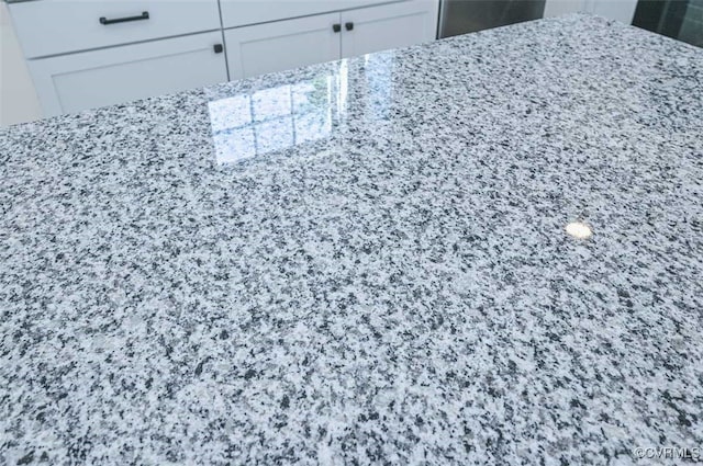 interior details featuring light stone countertops and white cabinetry