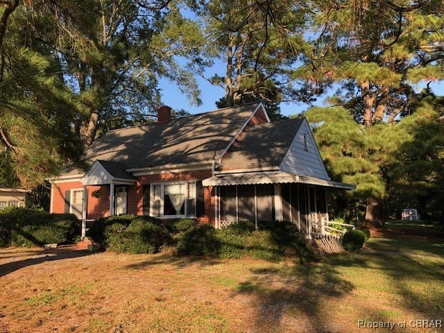 view of front of house featuring a sunroom and a front lawn