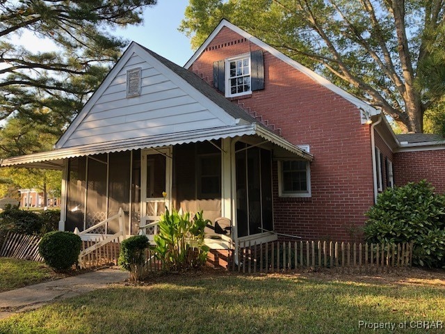 view of front facade featuring a sunroom and a front lawn