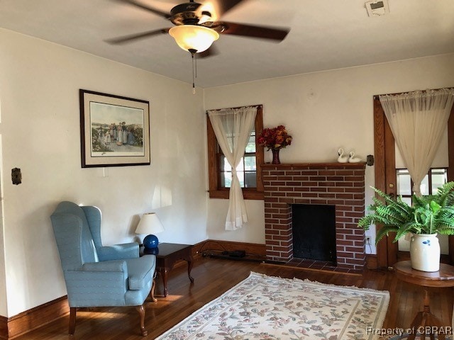 living area with hardwood / wood-style flooring, a brick fireplace, and ceiling fan