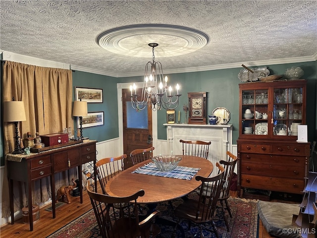 dining space featuring ornamental molding, hardwood / wood-style flooring, and a textured ceiling