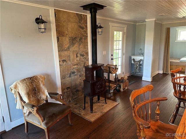 living area with a wood stove, crown molding, and dark hardwood / wood-style flooring